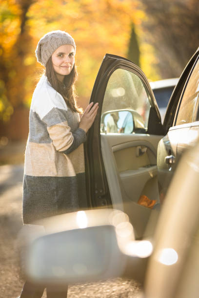 istock Pretty young woman by her car 1351002463