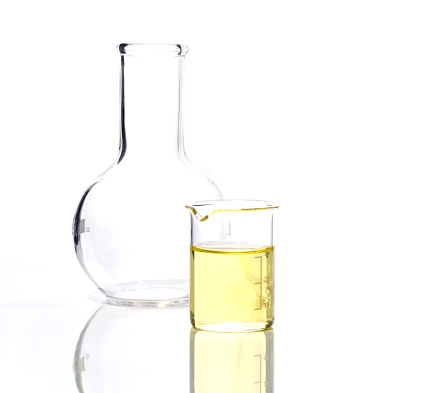 Cosmetic chemical ingredient on white laboratory table. Poly Aluminium chloride liquid in beaker place next to Flat Bottom Flask (Borosilicate Glass). Side View