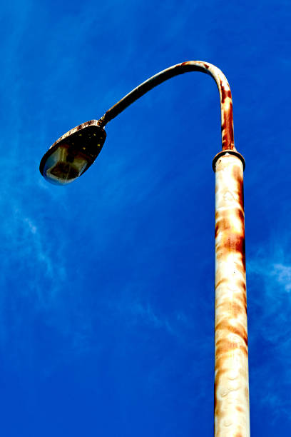 an old rusty lamppost against the blue sky rusty modern street lamppost with a broken lamp against the blue sky. rusty pole stock pictures, royalty-free photos & images