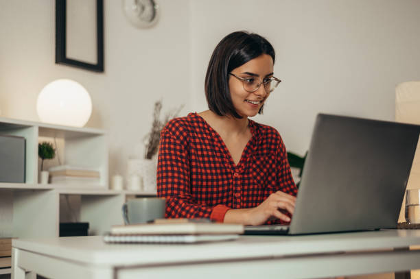istock Beautiful woman using a laptop while working from home 1351004762