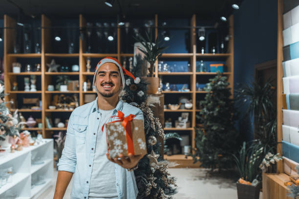 istock Smiling  young man in Santa hat with gift boxes. 1351008025