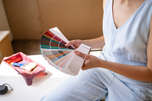 Cans of colorful paints and brushes on pink table, closeup