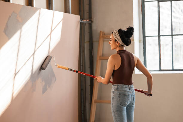 istock Cheerful Woman Painting Panel with Paint Roller 1351008609