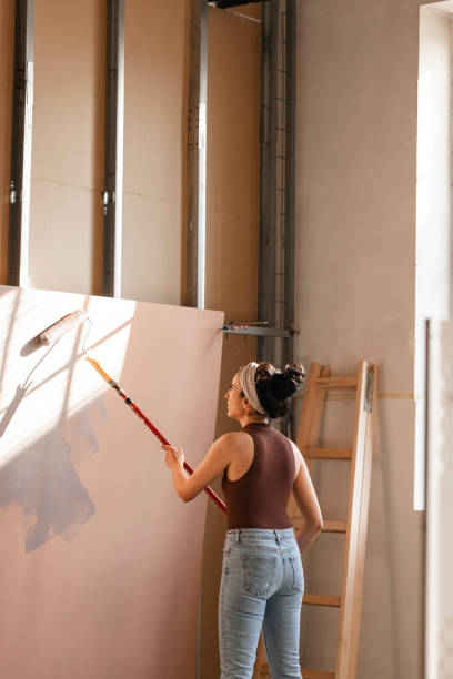 istock Young Woman Painting Panel with Paint Roller 1351008617
