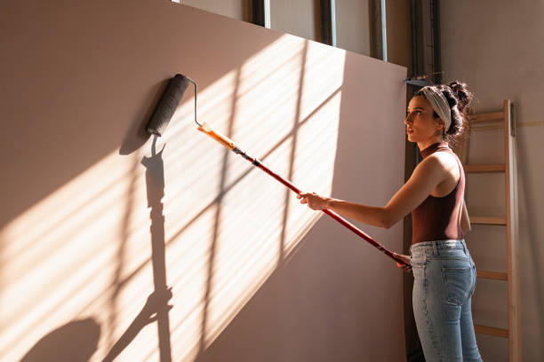 istock Beautiful Woman Painting Panel with Paint Roller 1351008618