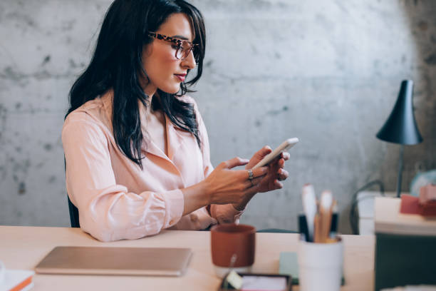 istock Beautiful Female Entrepreneur Using her Smartphone while Working at the Office 1351009944