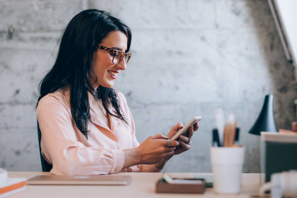 istock Happy Female Entrepreneur Using her Smartphone while Working at the Office 1351009946