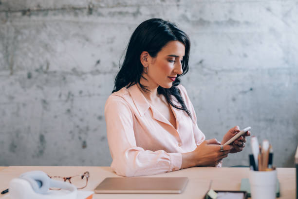 istock Beautiful Female Entrepreneur Using her Smartphone while Working at the Office 1351009957