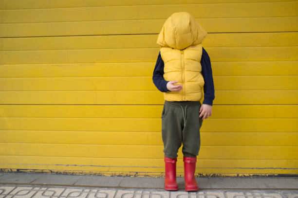 istock Little boy hides his face with his coat hood 1351014613