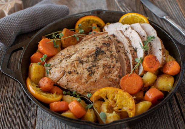 Roasted turkey breast with fried potatoes and caramelized vegetable Delicious and homemade cooked slow cooker roast turkey breast. Served with fried potatoes and caramelized carrots with oranges isolated on wooden table. celebrity roast stock pictures, royalty-free photos & images