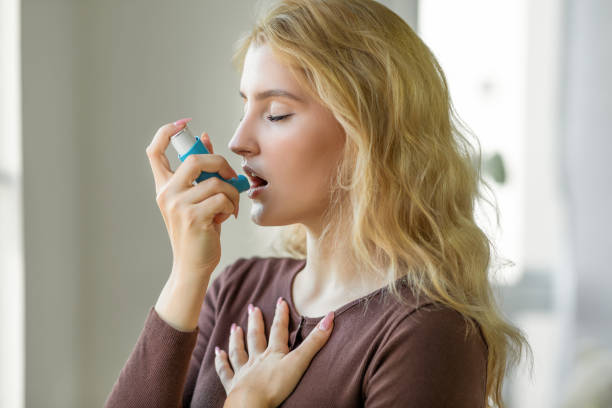 frau mit asthma-inhalator - asthmatisch stock-fotos und bilder
