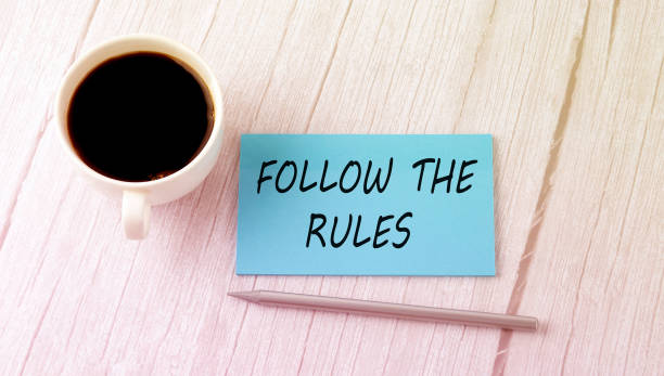 istock FOLLOW THE RULES text on the blue sticker with cofee and pen 1351021981
