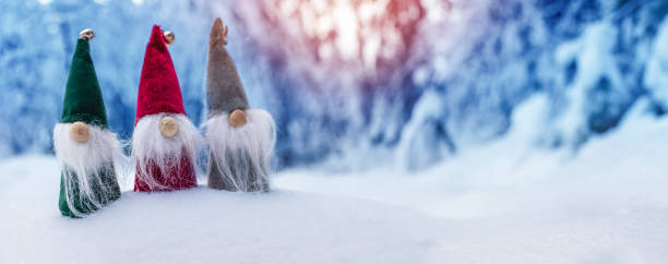 Three cute gnomes in the snowdrift in the winter forest. Beautiful view of the snowy background in natural park.
