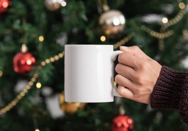 istock women hand holding white ceramic coffee cup with christmas tree background. mockup mug for creative advertising text message. 1351024415