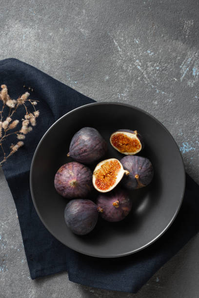 istock Overhead view organic sliced and whole fresh figs in bowl on dark background 1351025362