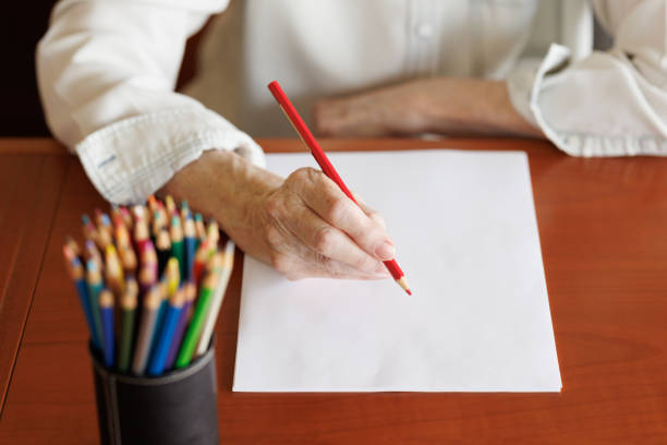 Elderly woman's hand with pencil about to write or draw.