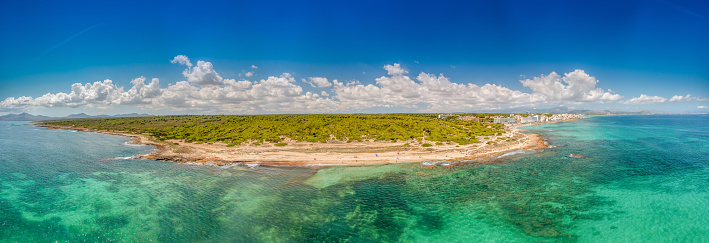 Wide panoramic aerial drone photo taken on the beautiful island of Majorca Mallorca in Spain showing the beach and sea front of the beach of Can Picafort on a bright sunny summers day