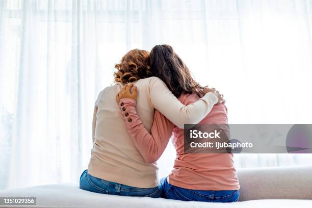 Rear View Of Mother And Daughter Embracing Sitting On Bed Stock Photo - Download Image Now