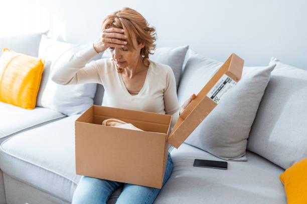 Angry shocked young woman unpacking parcel at home