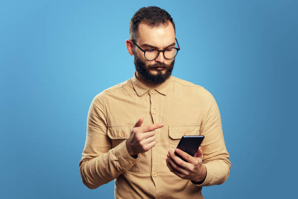 istock Serious handsome caucasian man using smartphone on blue background 1351035143