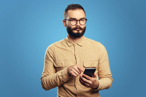 istock Serious handsome caucasian man using smartphone on blue background 1351035966