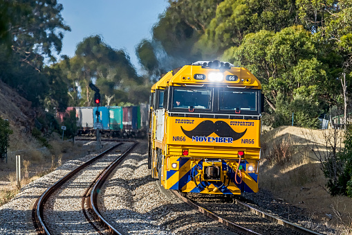 Adelaide, Australia - July 1, 2021: Movember - Promoting men's health on the front of a freight train. Pacific National's diesel locomotive NR66 has been given a moustache on its \