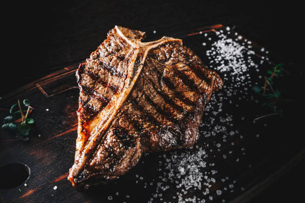 istock Grilled T-bone Steak on bones on wooden board on dark background 1351041808