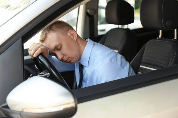 istock Tired young man sleeping on steering wheel in his car 1351042042