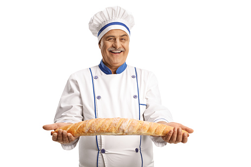 Cheerful male chef holding a baguette bread isolated on white background