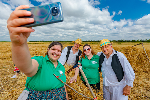 Muzlja, Vojvodina, Serbia, - July 03, 2021; XXXVIII Traditionally wheat harvest. Woman takes selfie with her friends after harvest, one more photo for the end.