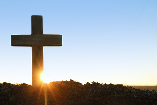 Wooden Christian cross outdoors at sunrise, space for text. Religion concept