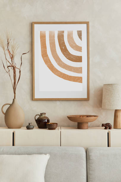 istock Creative composition of stylish living room interior with mock up poster frame, sofa, commode, clay vases and stylish personal accessories. Pastel neutral colours. Template. 1351043147
