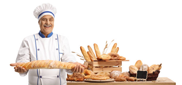 istock Mature male chef holding a baguette bread in front of a table with different breads 1351043676