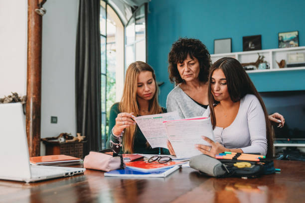 A mother is helping her daughter and a friend with the homework A mother is helping her daughter and a friend with the homework. They are at home, preparing themselves for the back to school. college student and parent stock pictures, royalty-free photos & images