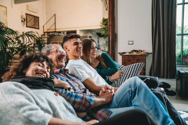 familie mit zwei heranwachsenden kindern schaut zu hause auf dem sofa fern - senior women electronics people remote control stock-fotos und bilder