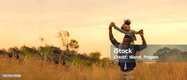 Happy African Family Child Daughter Riding The Neck Father And Running On Meadow Nature On Silhouette Lights Sunset Travel And Family Concept Stock Photo - Download Image Now