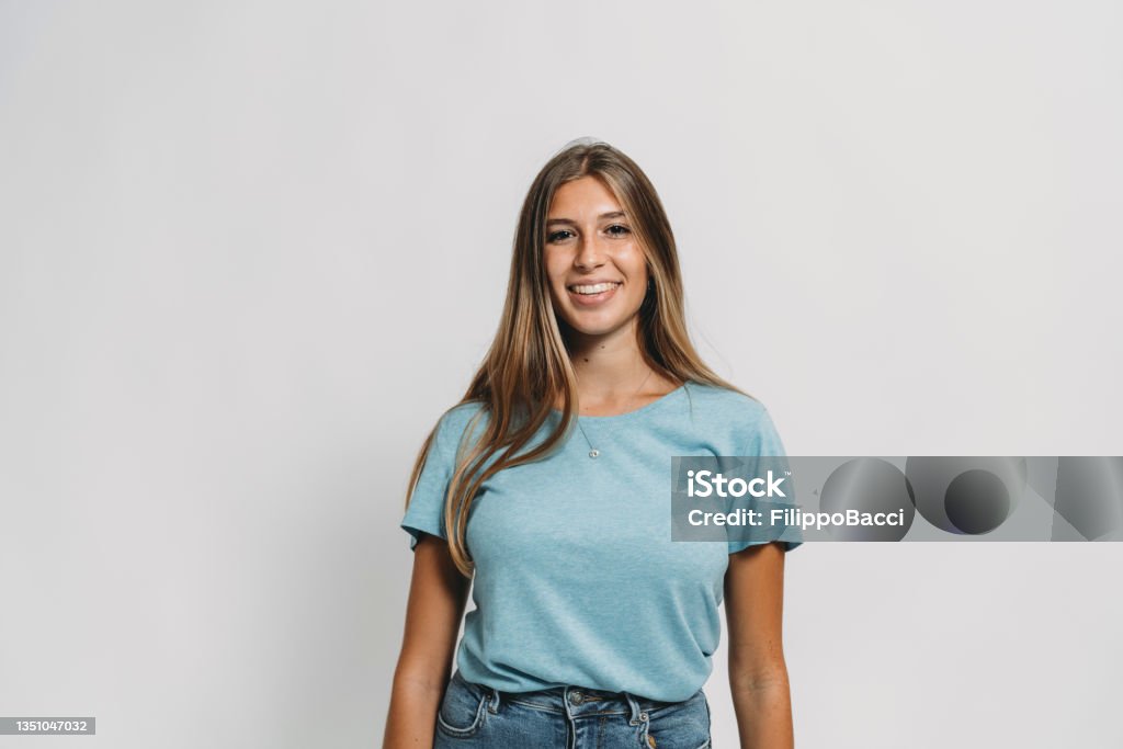 Portrait of a young adult woman against a white background Portrait of a young adult woman against a white background. She's looking at camera. Portrait Stock Photo