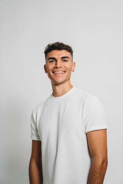 Portrait of a young adult man against a white background Portrait of a young adult man against a white background. He's standing, looking at camera. italian ethnicity stock pictures, royalty-free photos & images