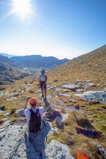 istock Hiking friends relax at trail summit, in grassy meadow 1351048169