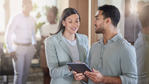 istock Shot of two coworkers talking while using a digital tablet 1351048701