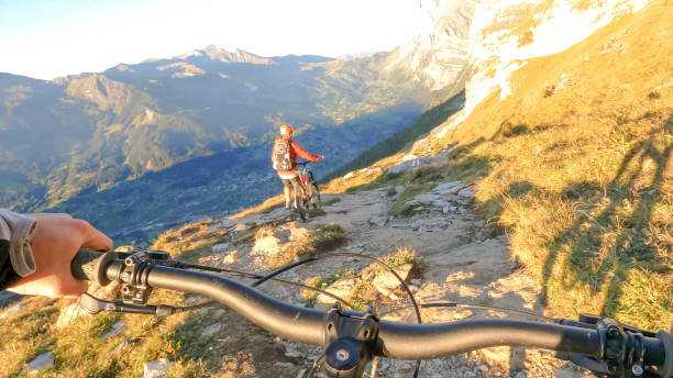 istock Man pushes mountain biker along trail in the Alps 1351048846