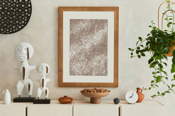 istock Creative composition of modern beige living room interior design with designed sculptures, mock up poster frame, beige wooden sideboard and personal accessories. Template. 1351049317