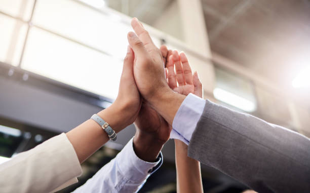 shot of a group of business people high fiving each other - excitement business person ecstatic passion imagens e fotografias de stock