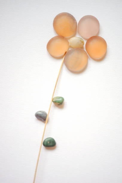 Orange flower made from glass stones on white paper.