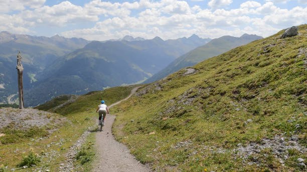 istock Female mountain biker follows trail down grass slope 1351060215