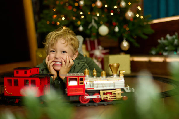 istock Happy curly-haired boy is playing with a magic toy train at the Christmas tree. 1351063089