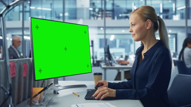 Diverse Modern Office: Confident Businesswoman Using Desktop Computer with Green Screen Mock Up Display. Manager Working on e-Commerce Support, Project Marketing, Data Analysis
