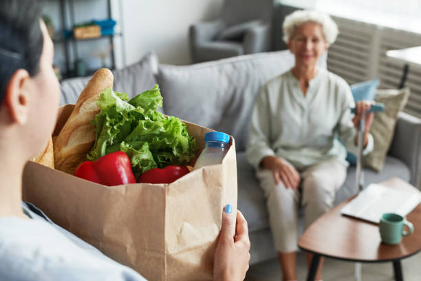 soignant livrant des produits d’épicerie à une femme âgée - sociology photos et images de collection