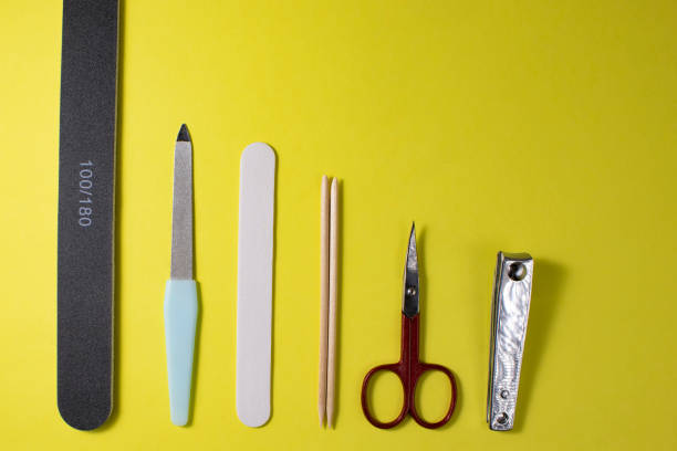 istock Tools for manicure on a yellow background, top view. A nail file, scissors, wooden cuticle sticks, nail oil on a yellow background, top view. 1351065021