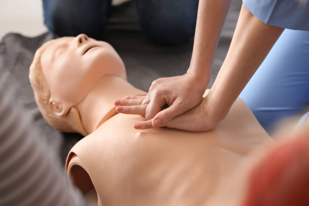 Instructor demonstrating CPR on mannequin at first aid training course stock photo